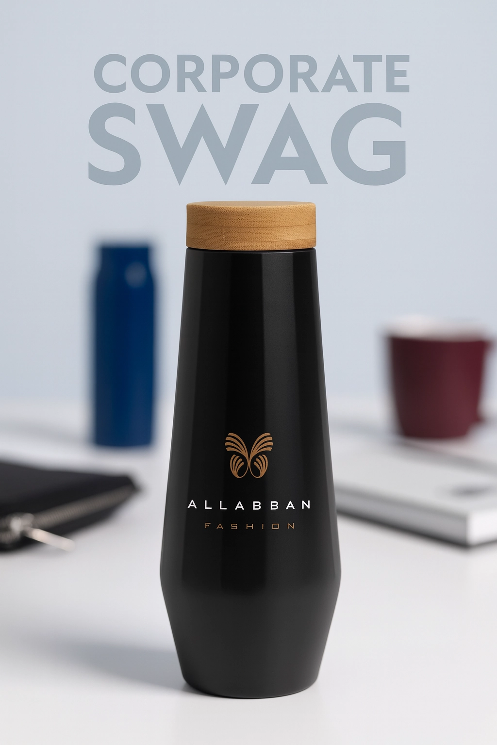 Matte black custom water bottle with bamboo lid and gold Allabban Fashion logo, placed on a modern desk surrounded by corporate swag items like notebooks and mugs, with 'CORPORATE SWAG' in bold text in the background.